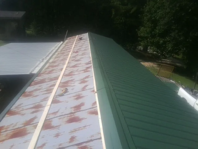 Old rusted panels beside newly installed green metal roofing — Wind Damage Roof Repair by Roofing Brothers in Leonia