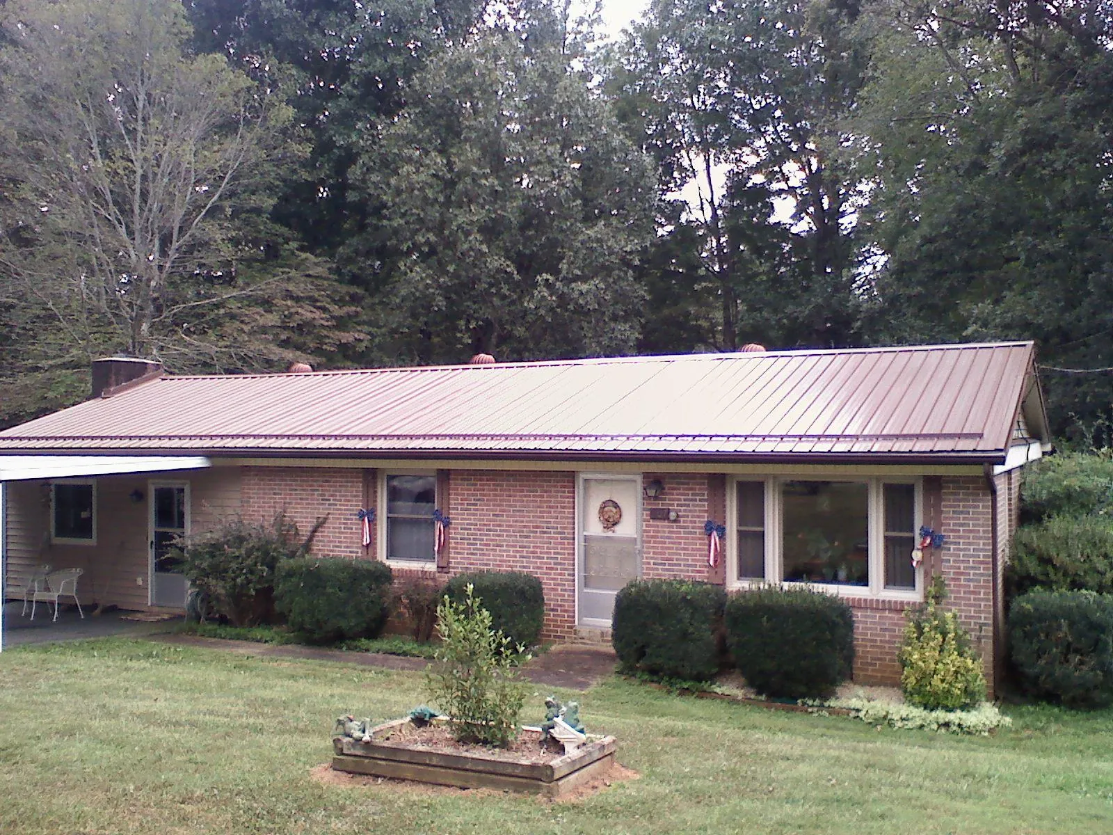 Bronze metal roof on a brick ranch home with a carport in Leonia