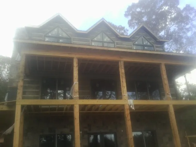 Dormers and porch framing on a large log home under construction — Roof Coating work by our crew in Leonia