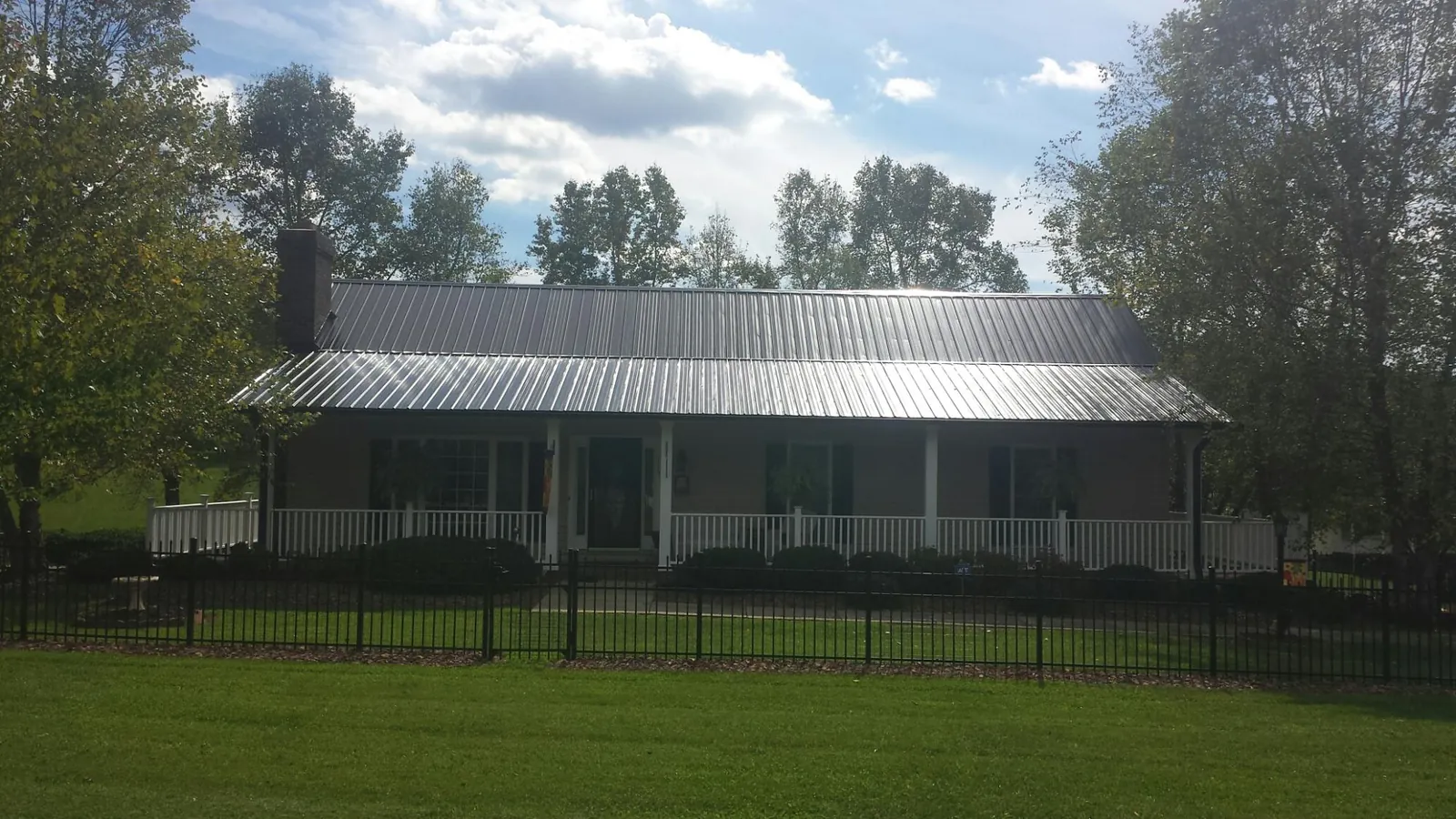 Gray metal roof on a brick ranch with a full width front porch — Gutter Guard Installation work by our crew in Leonia