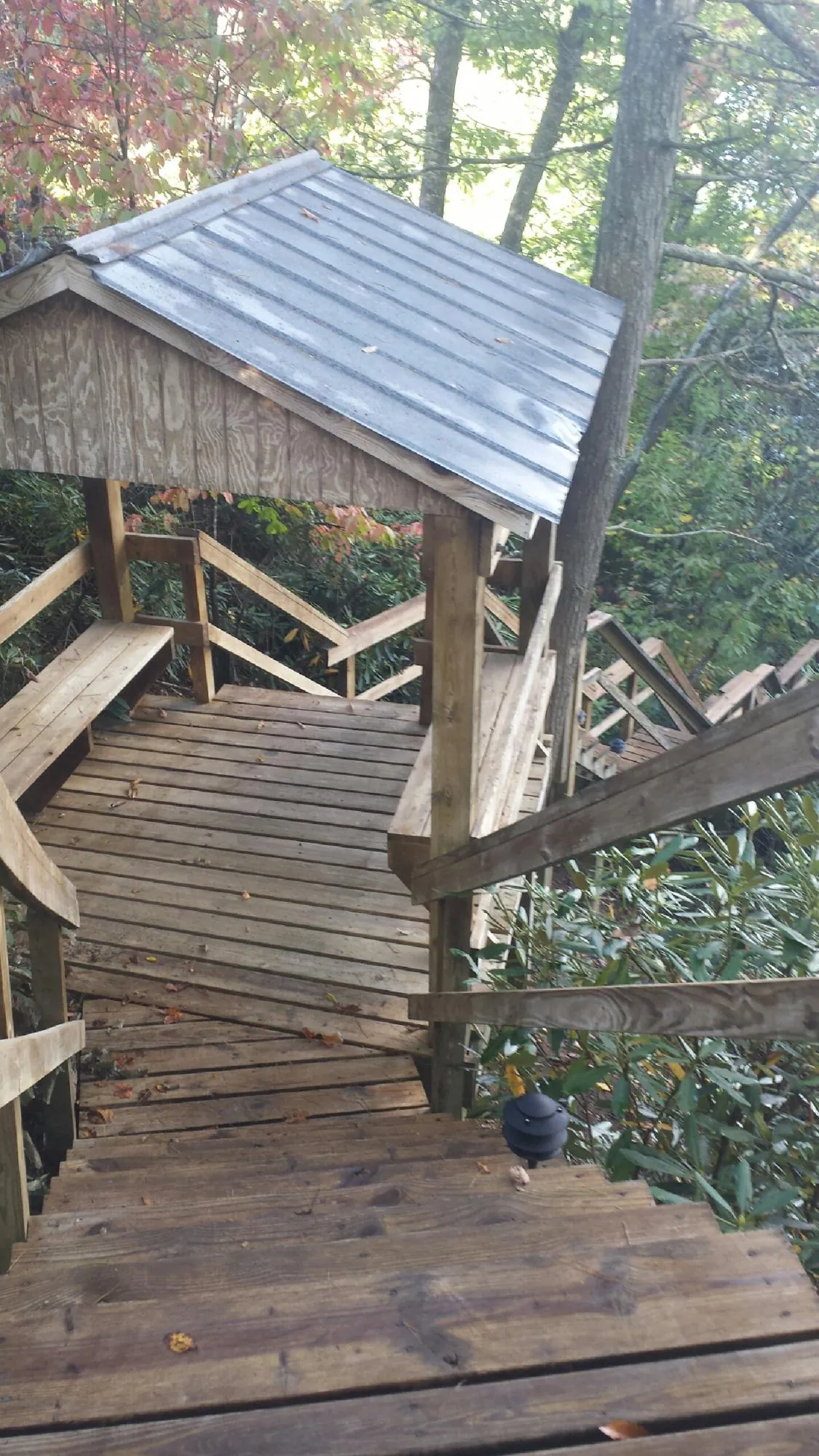 Metal roofed shelter over wooden steps on a wooded walkway — Skylight Repair & Installation work by our crew in Leonia