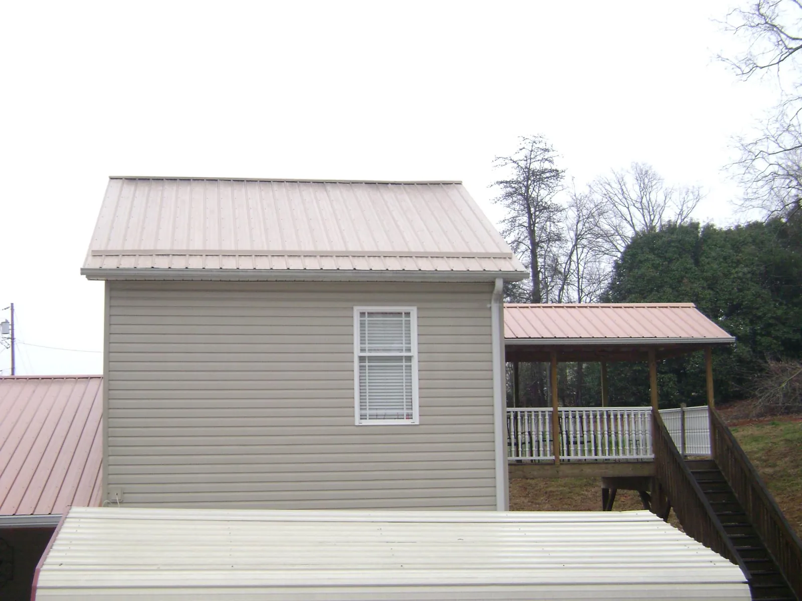 Tan metal roofs on a two story addition and attached porch, from a Roof Replacement job in Leonia