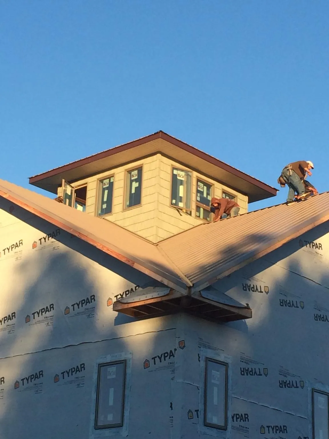 Roofers working around a rooftop cupola on a new metal roof at sunset — Roof Waterproofing in Leonia by Roofing Brothers